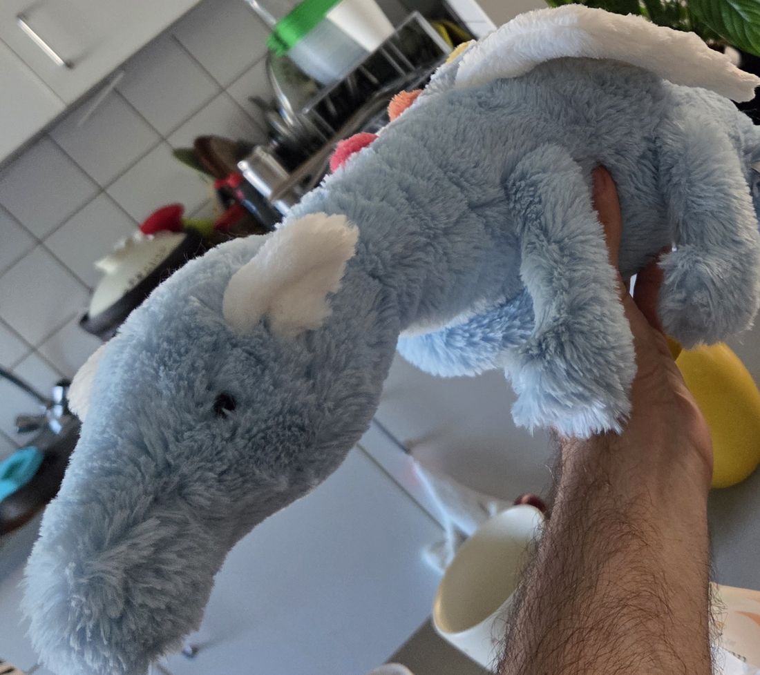 Close view of the plush elephant's head, cream inner ears and long soft trunk.